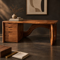 Corner detail of executive desk with oval ring leg and curved back panel beside wood, brass and linen samples