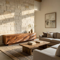 TV cabinet with four faceted sculpted doors in a sunlit room with large windows and plants