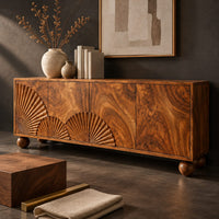 Corner detail of wooden sideboard with fan carved relief on four door fronts and ball feet beside wood, brass and linen samples
