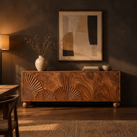 Wooden sideboard with fan carved relief on four door fronts and ball feet in a dark dining room at golden hour