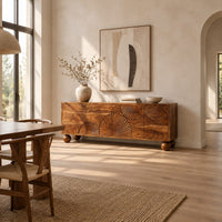 Sideboard with fan shaped carvings across four doors and ball feet in a bright open plan dining room