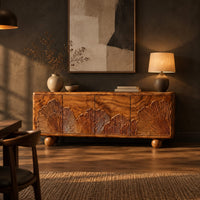 Sideboard carved with fan shaped leaves on four doors and ball feet in a dark dining room at golden hour