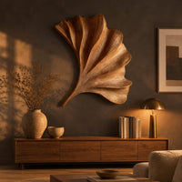 Fan shaped carved leaf wall art with radiating ribs and a curved stem above a low console in an evening living room