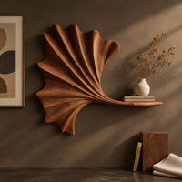 Detail of fan shaped leaf wall art with carved ribs and a small ledge beside wood, brass and linen samples