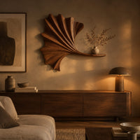 Fan shaped leaf wall art with carved ribs and a small ledge above a low console in an evening living room
