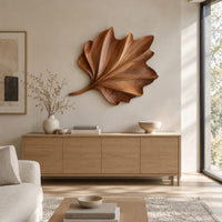 Fan shaped wooden leaf with raised ribs and a ruffled edge above a light oak sideboard in daylight