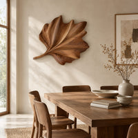 Fan shaped wooden leaf with raised ribs and a ruffled edge beside a dining table in natural light