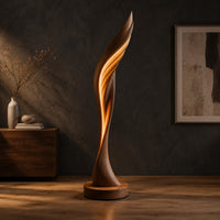 Tall twisting floor lamp shaped like a leaf with a glowing seam in a dark studio against a charcoal plaster wall