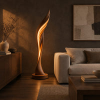 Tall twisting floor lamp shaped like a leaf with a glowing seam in a dark living room at golden hour