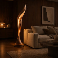 Tall twisting floor lamp shaped like a leaf with a glowing seam in an evening living room with walnut wall paneling