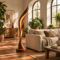 Tall twisting floor lamp shaped like a leaf with a glowing seam in a bright living room with arched windows and plants