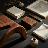 Corner detail of figure eight base coffee table beside wood, brass and linen samples