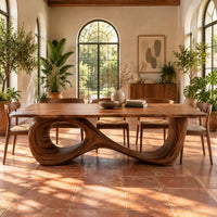 Dining table with a flowing figure eight loop base in a bright dining room with arched windows and plants