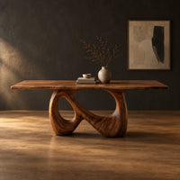 Dining table on a single figure eight loop base with two open holes in a dark studio against a charcoal plaster wall