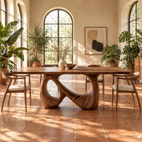 Dining table on a single figure eight loop base with two open holes in a bright dining room with arched windows and plants