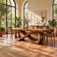 Rectangular dining table on a figure eight loop base with a thick plank top in a bright dining room with arched windows and plants