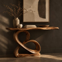 Corner detail of console table with a figure eight wooden pedestal and a narrow natural edge top beside wood, brass and linen samples