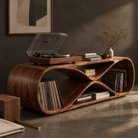 Corner detail of low record console shaped like a figure eight with open bays at each end beside wood, brass and linen samples