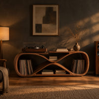 Low record console shaped like a figure eight with open bays at each end in a dark living room at golden hour