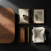 Corner detail of low loop TV stand with carved figure eight openings beside wood, brass and linen samples