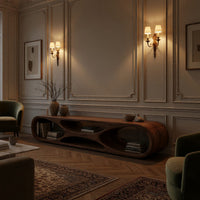 Low loop TV stand with carved figure eight openings in an evening room lit by two lamps
