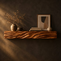 Thick mantel beam with a carved wave pattern along the front in a dark studio against a charcoal plaster wall