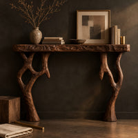 Corner detail of fireplace mantel with a carved top slab and twisted branch shaped legs beside wood, brass and linen samples