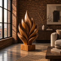 Flame shaped sculpture of layered carved leaves on a square wooden base in an industrial loft living room with exposed brick