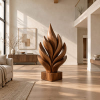 Flame shaped sculpture of layered carved leaves on a square wooden base in a bright open plan living room
