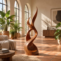 Flame shaped wood sculpture with two pointed tips and a swirling base in a bright living room with arched windows and plants