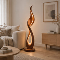 Flame shaped floor lamp with a glowing teardrop opening on a disc base in a Scandinavian living room with white walls