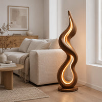 Flame shaped wooden floor lamp with a glowing loop on a disc base in a Scandinavian living room with white walls