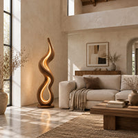 Flame shaped wooden floor lamp with a glowing loop on a disc base in a bright open plan living room