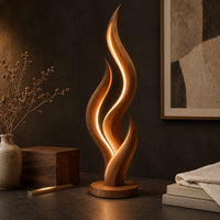 Corner detail of flame shaped floor lamp with layered tongues and a glowing seam beside wood, brass and linen samples