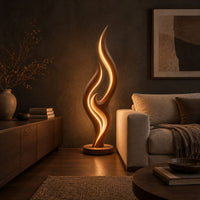 Tall flame shaped floor lamp with layered wooden ribbons on a disc base in a dark living room at golden hour