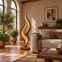 Tall flame shaped floor lamp with layered wooden ribbons on a disc base in a bright living room with arched windows and plants