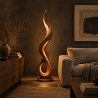 Flame shaped floor lamp with an open loop base and inner glow in a dark living room at golden hour