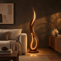 Flame shaped floor lamp with an open teardrop loop and a glowing edge in a dark living room at golden hour