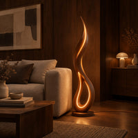 Flame shaped floor lamp with an open teardrop loop and a glowing edge in an evening living room with walnut wall paneling