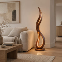 Flame shaped floor lamp with an open teardrop loop and a glowing edge in a Scandinavian living room with white walls