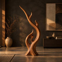 Flame shaped wood sculpture with a long sweeping arm and an open loop in a dark living room at golden hour