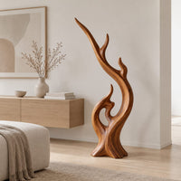 Flame shaped wood sculpture with a long sweeping arm and an open loop in a Scandinavian living room with white walls