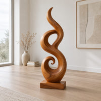 Flowing flame sculpture with a spiral scroll at its foot and a block base in a Scandinavian living room with white walls