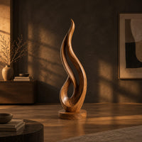 Flame shaped wood sculpture with an open loop on a disc base in a dark living room at golden hour