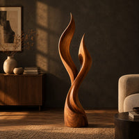 Wood sculpture shaped like two rising flames with smooth swept lines in a dark living room at golden hour