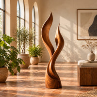 Wood sculpture shaped like two rising flames with smooth swept lines in a bright living room with arched windows and plants