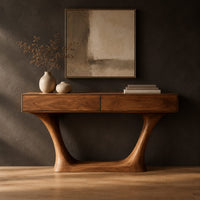 Console table with two flat front panels, flared legs and an oval base in a dark studio against a charcoal plaster wall