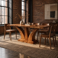 Rectangular dining table with two flared pedestal legs on a stepped plinth in an industrial loft dining room with exposed brick