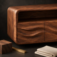 Corner detail of floating vanity cabinet with carved wave fronts and an open top niche beside wood, brass and linen samples
