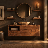 Floating wooden vanity cabinet with leaf and wave carved fronts and an open niche in a dark bathroom at golden hour